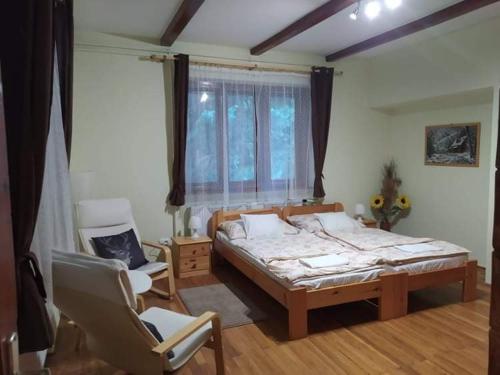 1 dormitorio con 1 cama, 1 silla y 1 ventana en Hamvaskői Vadászház, en Pilismarót