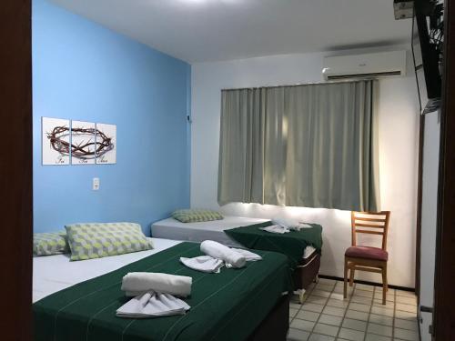 um quarto com duas camas com lençóis verdes e uma cadeira em Por do Sol Pousada Praia em São Luís