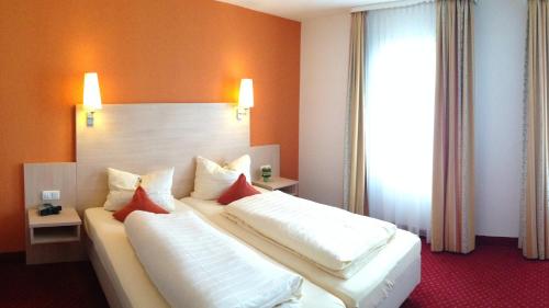 a bedroom with a large bed with white sheets and red pillows at Hotel Café Konditorei Köppel in Bingen am Rhein