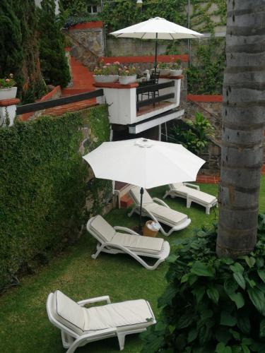 a group of chairs and an umbrella on a lawn at Casa Dalinda in Valle de Bravo