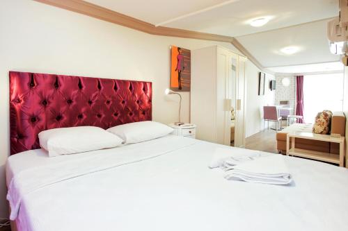 1 dormitorio con 1 cama blanca grande y cabecero rojo en Detay Suites Taksim, en Estambul