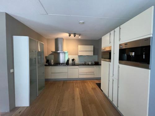 a kitchen with white cabinets and a hard wood floor at VILLA CALMA Rust Ruimte Luxe inclusief private jacuzzi in Zeewolde