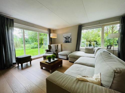 a living room with a couch and chairs and windows at VILLA CALMA Rust Ruimte Luxe inclusief private jacuzzi in Zeewolde