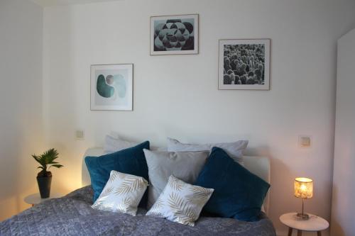 City Living near ICE/1&1/Fashion Outlet Montabaur في مونتابور: غرفة نوم مع سرير ووسائد زرقاء وبيضاء