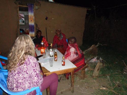 un groupe de personnes assises à une table dans une pièce dans l'établissement Maasai homestay camping, à Sekenani