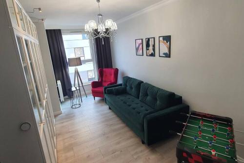 salon z zieloną kanapą i czerwonym krzesłem w obiekcie Apartament3City w Gdańsku