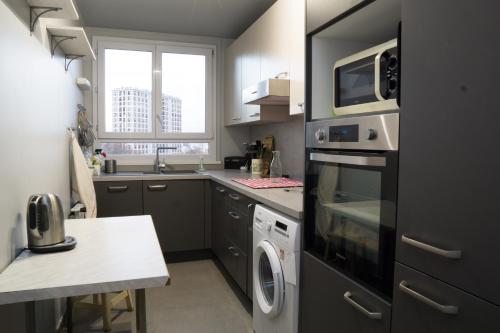 La cuisine est équipée d'un four micro-ondes, d'un lave-linge et d'un sèche-linge. dans l'établissement EXIGEHOME Grand T2 proche Paris Porte d'Orléans, à Châtillon