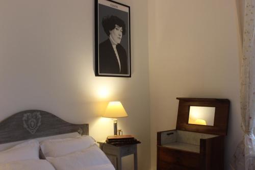 a bedroom with a bed and a picture on the wall at Il était une fois un jardin in Saint-Fargeau