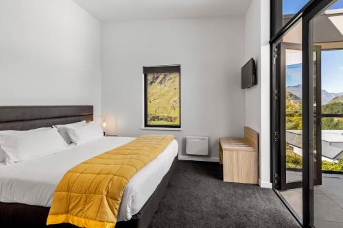 a bedroom with a large bed with a yellow blanket at Riverview Penthouse - Apartment 19 in Queenstown