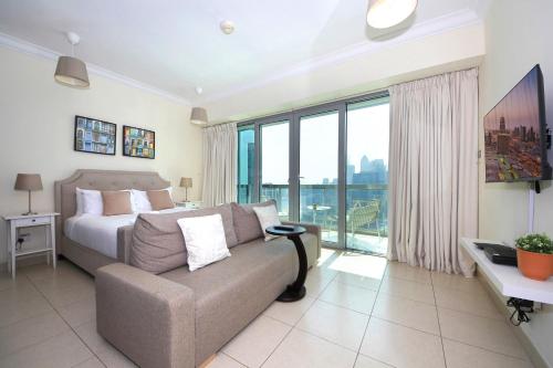 a bedroom with a couch and a bed with a large window at Prime Retreats - Downtown Dubai in Dubai