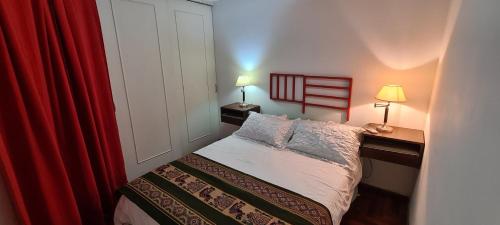 a small bedroom with a bed and a red curtain at Departamento Boutique en Nueva Córdoba in Cordoba