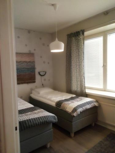 Un dormitorio con dos camas individuales y una ventana. en Jokihelmi-apartment, en Kannus