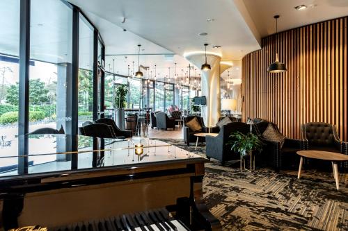 a lobby with tables and chairs and a piano at Novotel New Plymouth Taranaki in New Plymouth