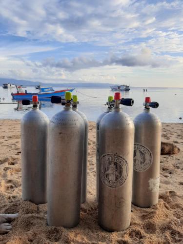 four metal containers sitting on the sand on the beach at Blue Shark Divers Bunaken in Bunaken