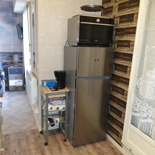 La cuisine est équipée d'un réfrigérateur en acier inoxydable et d'un four micro-ondes. dans l'établissement Appartement studio proche mer 4 pers résidence calme avec parc, à Blonville-sur-Mer
