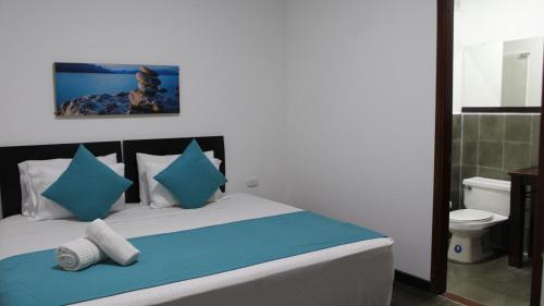 a bedroom with a bed with blue and white pillows at Hotel Los Cristales in Santa Rosa de Cabal