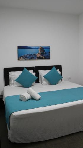 a large bed with blue and white pillows on it at Hotel Los Cristales in Santa Rosa de Cabal