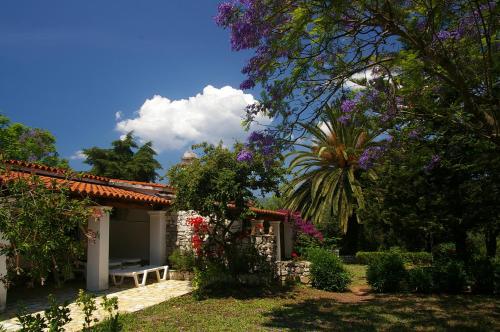 a garden with a bench and trees and flowers at Marialice in Dassia