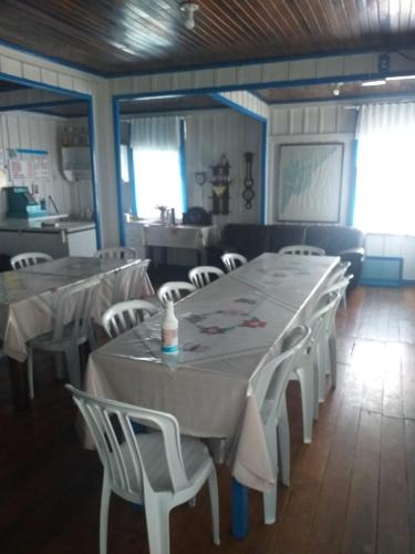 een eetkamer met witte tafels en witte stoelen bij Dona Quinota in Ilha do Mel