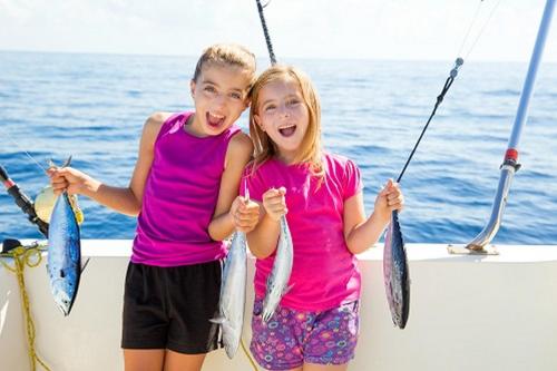 two young girls holding fish on a boat at Hotel Indigo Orange Beach - Gulf Shores by IHG in Gulf Shores