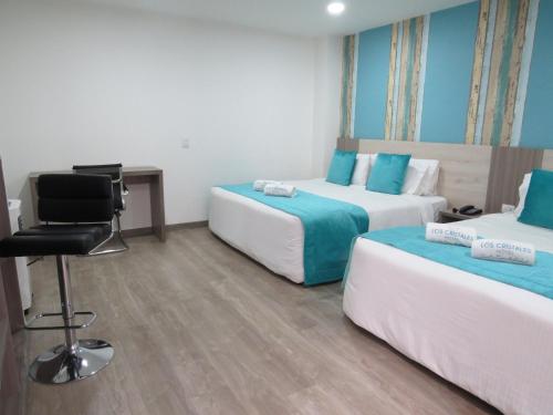 a hotel room with two beds and a desk at Hotel Los Cristales in Santa Rosa de Cabal