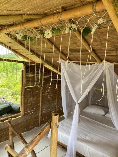 a bed in a thatched hut with white curtains at biohotel tatacoa Qji in Villavieja