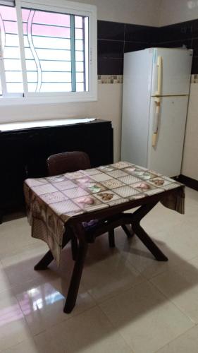 a table in a kitchen with a refrigerator at Appartement abdessalam fetouaki in Moulay Yacoub