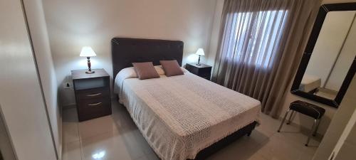 a bedroom with a bed with two lamps and a mirror at Departamento 1 dormitorio en complejo con amenities - Córdoba Ciudad in Cordoba