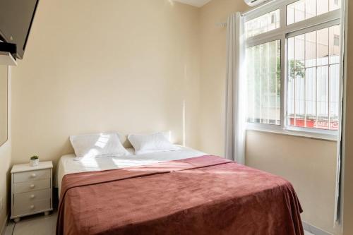 1 dormitorio con 1 cama con manta roja y ventana en Apartamento Copa Suiça, en Río de Janeiro