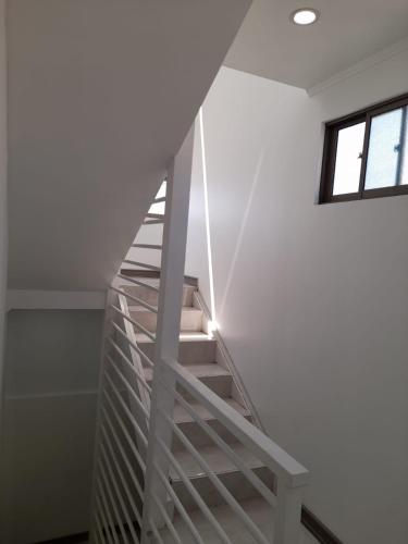 a white staircase in a white room with a window at Hostal Paraiso Tocopilla in Tocopilla