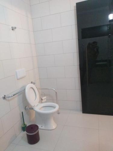 a bathroom with a toilet and a black door at Balli Suítes in Ilha Comprida