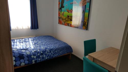 a small bedroom with a bed and a painting on the wall at Quiet spacious room in Amsterdam