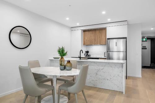 a white kitchen with a white table and chairs at Koko Broadbeach in Gold Coast