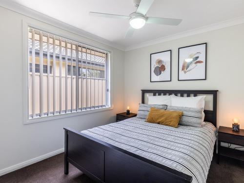 a bedroom with a bed and two windows at 15 Oasis Close Soldiers Point in Soldiers Point