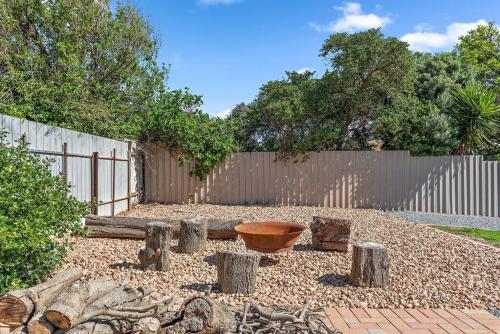 a garden with logs and a wooden fence at Kokomo - Silver Sands - C21 SouthCoast Holidays in Aldinga Beach