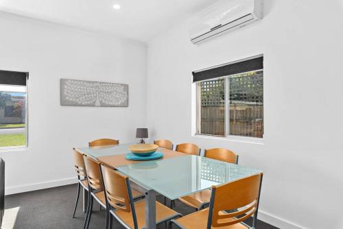 Un comedor con una mesa de cristal y sillas. en Kokomo - Silver Sands - C21 SouthCoast Holidays, en Aldinga Beach