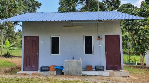 a small house with a blue roof and three doors at Chalet Kampong Semawar in Kuala Kangsar