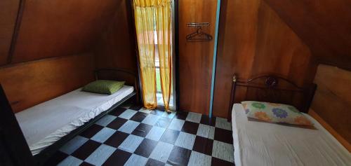 a small room with two beds and a checkered floor at Chalet Kampong Semawar in Kuala Kangsar