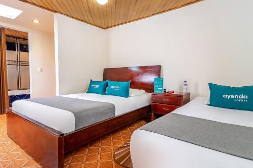 pokój hotelowy z 2 łóżkami i niebieskimi poduszkami w obiekcie Ayenda Nabusimake w mieście Bogota