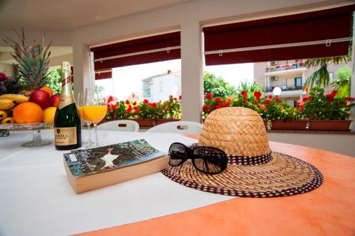 einen Hut und ein Buch und eine Flasche Wein auf dem Tisch. in der Unterkunft Villa Fontana in Sukošan