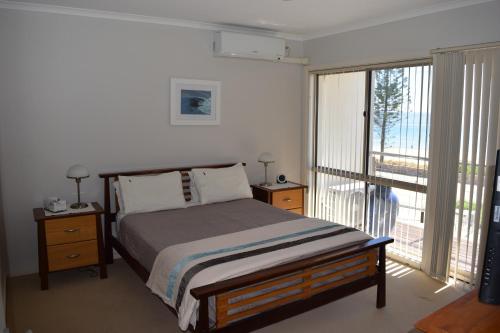 a bedroom with a bed and a large window at Christies Seahorse Holiday Townhouses in Port Noarlunga