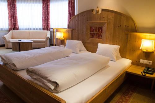 two beds in a room with a wooden headboard at Alpin Panoramahotel Lärchenhof in Heiligenblut