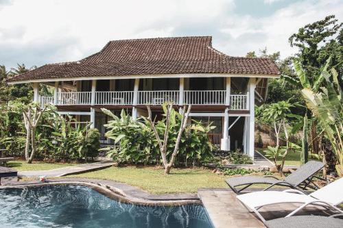 a house with a swimming pool in front of a house at Anggrek Putih Homestay & Cooking Class in Senggigi