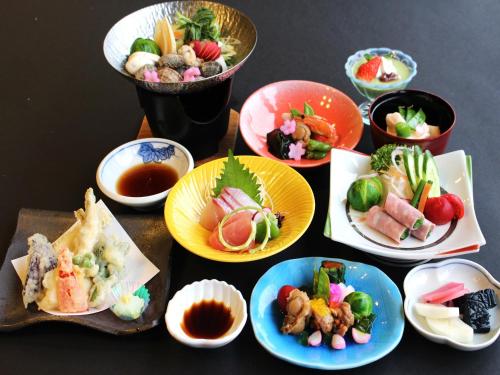 
a table topped with plates of food and bowls of food at Hotel Wellness Notoji in Hakui
