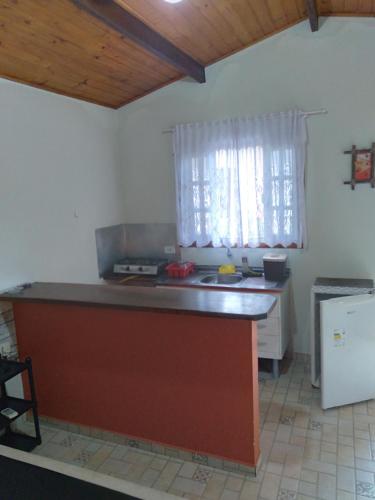 a kitchen with a counter and a sink and a window at Chalés Bangalôs Itamambuca in Ubatuba