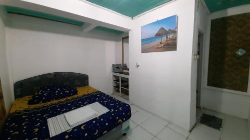 a small bedroom with a bed and a painting on the wall at Villa Family Pantai Citepus Pelabuhanratu in Citepus