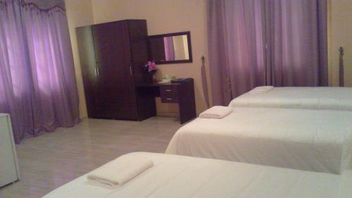 a hotel room with two beds and a dresser at Hotel Danat Al Khaleej in Ḩilf