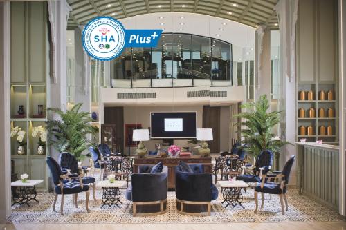 a hotel lobby with tables and chairs and a tv at Hotel Tranz in Bangkok
