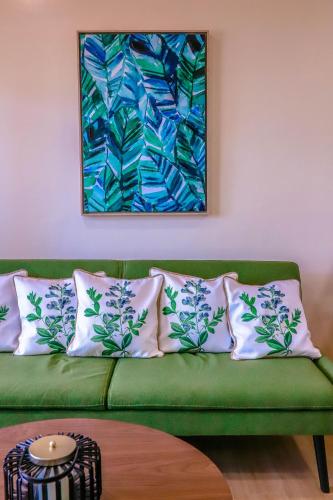 a green couch with pillows and a painting on the wall at Noni's Resort in Alitagtag