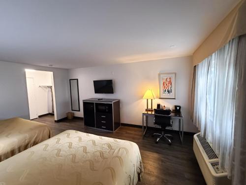 a hotel room with two beds and a desk and a television at Quality Inn Burbank Airport in Burbank